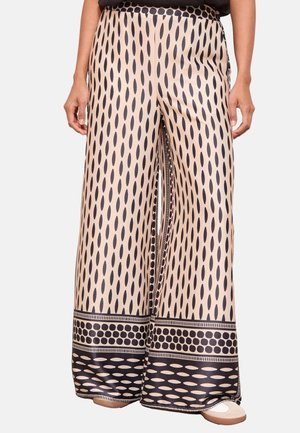 Beige wide-leg pants with vertical black oval patterns and contrasting black borders with dot and oval designs at the hem.