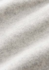 Tissu doux, gris clair avec une texture tissée subtile et des plis délicats créant une surface lisse et confortable.