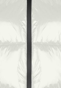 Giacca a vento gonfiabile con un esterno bianco lucido, caratterizzata da una cerniera e cuciture nere. Il design include un motivo trapuntato per l'isolamento.