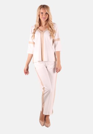 Women's outfit featuring a cream top with V-neck and three-quarter sleeves, paired with cream pants accented with beige side panels.