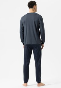 Męski zestaw odzieży domowej składający się z granatowej long-sleeve koszulki z teksturowanym wzorem oraz dopasowanych jednokolorowych granatowych spodni, oba w luźnym kroju.