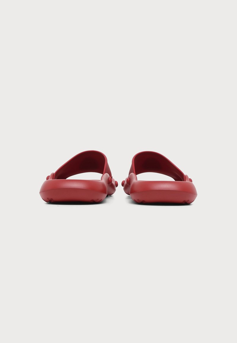 Paar rote Gummi-Slidesandalen, von hinten auf weißem Hintergrund gezeigt.