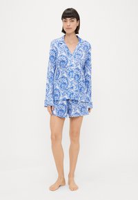Blue patterned pajama set featuring a button-up long-sleeve shirt and matching shorts, made of soft fabric with a paisley design.