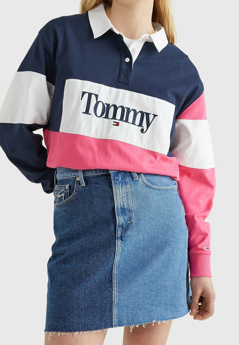 Langärmliges Rugby-Shirt in Marineblau, Weiß und Pink mit Kragen und "Tommy"-Logo. Kombiniert mit einem blauen Jeansrock mit fransigem Saum.