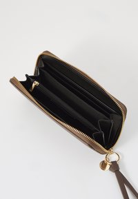 Brun pung med lynlås, guld hardware, flere kortholdere, en lynlåslomme og en håndledsrem, med en glat tekstur og elegant design.