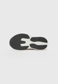 Suela de zapato con una superficie de goma texturizada negra y una entresuela blanca, con un diseño en patrón para el agarre y la flexibilidad.