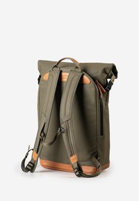 Olivgrüner Roll-Top-Rucksack mit gepolsterten Trägern, hellbraunen Lederakzenten, seitlichem Reißverschluss und verstellbaren Schnallen, aufrecht stehend vor weißem Hintergrund.