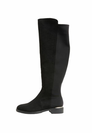 Crne čizme iznad koljena koje sadrže kombinaciju glatkih i teksturiranih materijala, ravnu petu i elegantan, prilagodljiv dizajn.