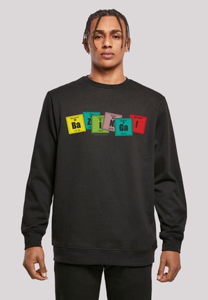 Black sweatshirt featuring colorful periodic table elements with text "Bazinga!" in bright red. Classic crew neck and ribbed cuffs.