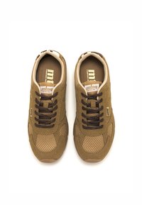 Zapatillas deportivas de malla y tela en color marrón con cordones marrones, acentos texturizados y un interior beige. Logo en la lengüeta y en el lateral. Suelas de goma planas.