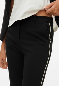 Črne hlače po meri s tesnim prileganjem, z belo bočno črto, gladko teksturo in diskretnim žepnim dizajnom.