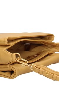 Sac à main en cuir tan avec fermoir doré, compartiment principal ouvert, poche zippée visible et détail de sangle réglable.