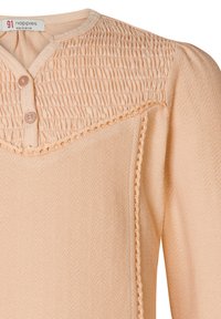 Brzoskwiniowa bluzka o fakturowanej części górnej z marszczeniem, okrągłym dekoltem i dwoma guzikami. Fakturowany materiał i delikatne detale.