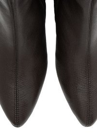 Botas de cuero texturizado marrón oscuro con punta afilada y costura vertical central en cada bota.