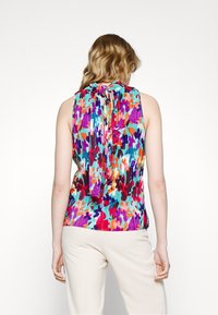 Blusa sin mangas colorida con un diseño plisado, que presenta un detalle de lazo en el cuello. La tela muestra un patrón floral en diferentes tonalidades.