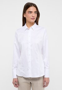 Witte blouse met lange mouwen van een gladde stof. Voorzien van een puntige kraag, knopen aan de voorkant en een getailleerde pasvorm.
