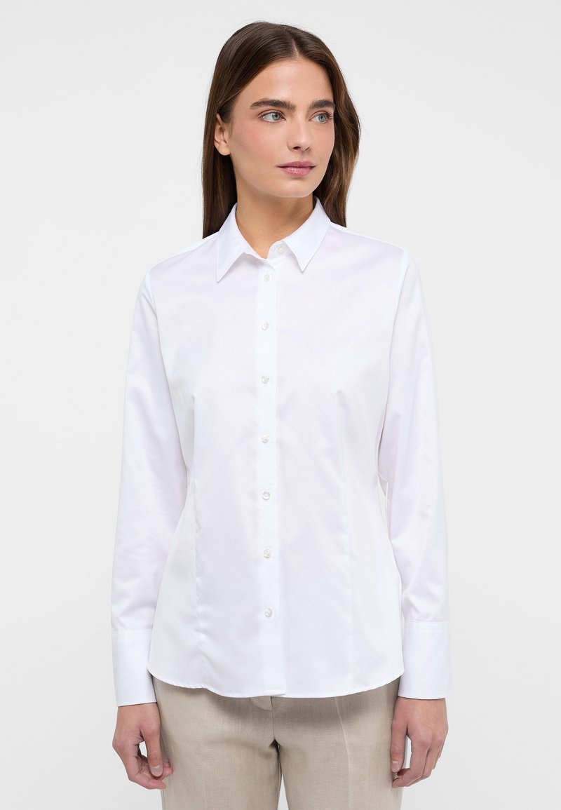 Witte blouse met lange mouwen van een gladde stof. Voorzien van een puntige kraag, knopen aan de voorkant en een getailleerde pasvorm.