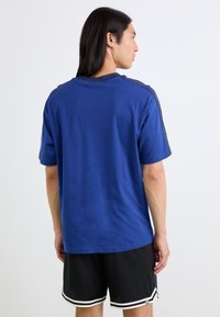 T-shirt en coton bleu avec un col rond, des manches courtes et un design simple. Le dos présente une texture sans couture sans détails supplémentaires.
