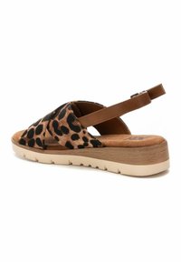 Sandalia de estampado de leopardo con diseño de tiras cruzadas, acentos de cuero marrón, plantilla suave y suela ligera y texturizada. Correa trasera ajustable.