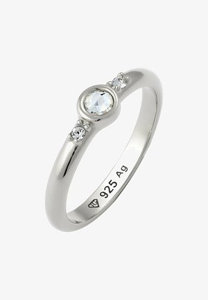 Bague en argent avec une finition polie, dotée d'une pierre précieuse ronde centrale et de deux pierres plus petites de chaque côté. Gravée avec "925 Ag."