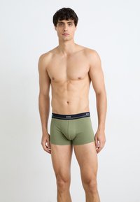 Khaki-grüne Boxershorts mit einem navyblauen elastischen Bund, der das "BOSS"-Logo trägt. Weicher Stoff, figurbetontes Design und mittellange Beine.