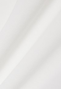 Tissu blanc texturé avec une surface lisse, présentant des motifs de tissage diagonaux. Le matériau semble léger et souple.