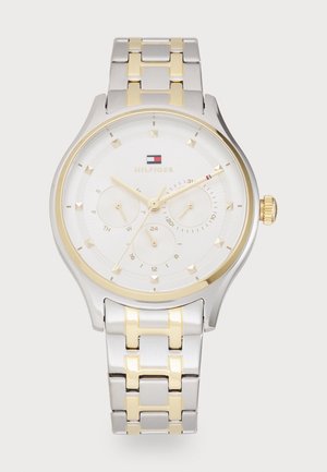 Montre-bracelet Tommy Hilfiger avec bracelet en métal argenté et doré, cadran blanc, trois sous-cadrans, index et aiguilles dorés.