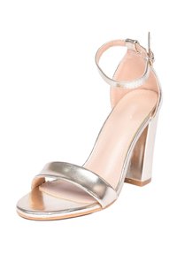 Sandalo con tacco alto in argento metallico, caratterizzato da una ampia fascia anteriore, cinturino alla caviglia con fibbia e un tacco spesso. Texture liscia e design con punta aperta.
