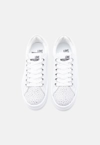 Ζευγάρι λευκά sneakers Love Moschino με σχέδιο δέσιμου και λαμπερά, διάτρητα καπάκια στα δάχτυλα.