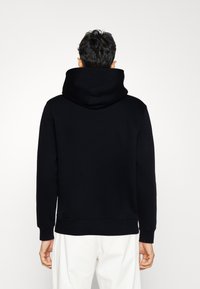 Black hooded sweatshirt with a relaxed fit, featuring a large hood and ribbed cuffs. Smooth texture, minimal design, and no visible logos.