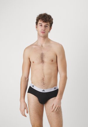 Black men's briefs with a white elastic waistband featuring Adidas logo accents. Soft fabric, snug fit, and a classic cut design.