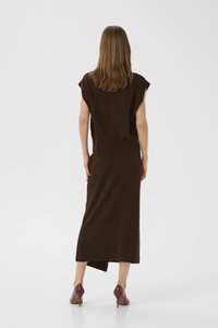 Brown, knitted dress with a fitted bodice and a flowing skirt; features short sleeves and an asymmetrical hem. Paired with burgundy heels.
