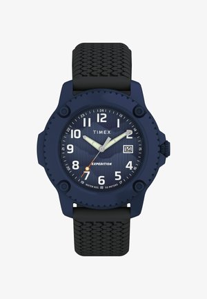 Tengerészeti kék Timex Expedition óra kerek tokkal, texturált gumiszíjjal, fehér óracímkékkel és narancssárga másodpercmutatóval a csíkos számlap ellen.