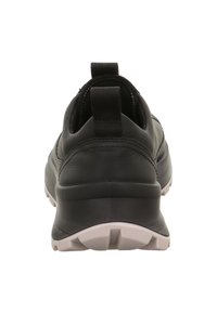 Sneaker in pelle nera con suola in gomma bianca spessa vista dal tallone, con linguette di apertura sul colletto posteriore.