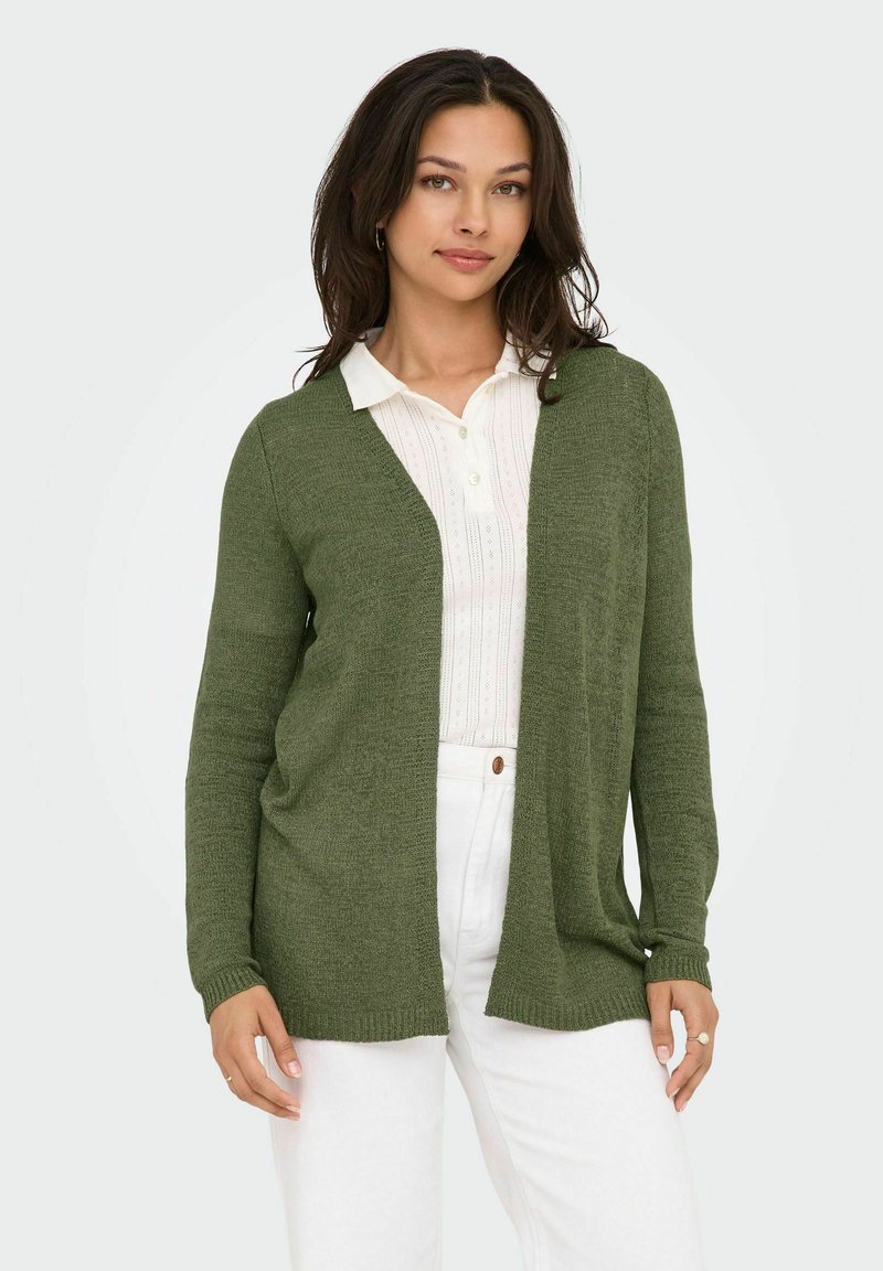Olivgrüner Strickcardigan mit offener Vorderseite, langen Ärmeln und legerer Passform, über einem weißen Hemd mit Kragen und dezentem Muster getragen.