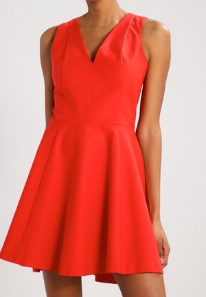 Robe sans manches rouge avec un décolleté en V, un corsage ajusté et une jupe évasée. Fabriquée en tissu lisse avec une couleur unie et sans motifs visibles.