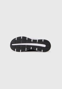 Zwart-witte rubberen zool van een sneaker met een profielpatroon en gesegmenteerde groeven voor flexibiliteit en grip.