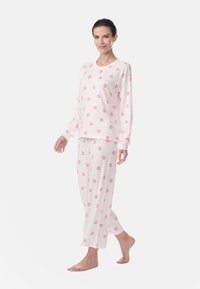 White pajama set featuring pink lip print, long-sleeve top and loose-fitting pants, made of soft fabric with a relaxed fit.