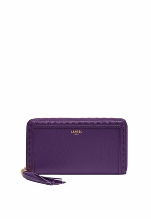 Portefeuille en cuir violet avec fermeture éclair tout autour, tirette à pompon, détails de couture en relief, et logo doré "LANCEL PARIS" au centre avant.