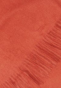 Écharpe rouge corail en tissu doux et texturé, avec des bords à franges et une apparence lisse et chaude.