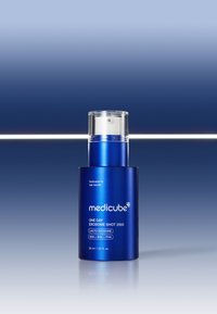 Bottiglia cilindrica blu con tappo a pompa trasparente. Presenta etichette con testo bianco "medicube", "ONE DAY EXOSOME SHOT 2000" e dettagli del prodotto.