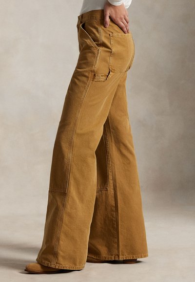 Hlače širokih hlačnic iz rjavega bombaža z teksturirano površino, z dvema zadnjima žepoma in izrazitim šivom ob šivih.