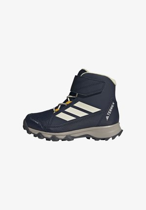 Navyblauwe hoge wandelschoen met witte Adidas strepen, klittenbandsluiting, robuuste zool en "TERREX" logo aan de hielzijde.