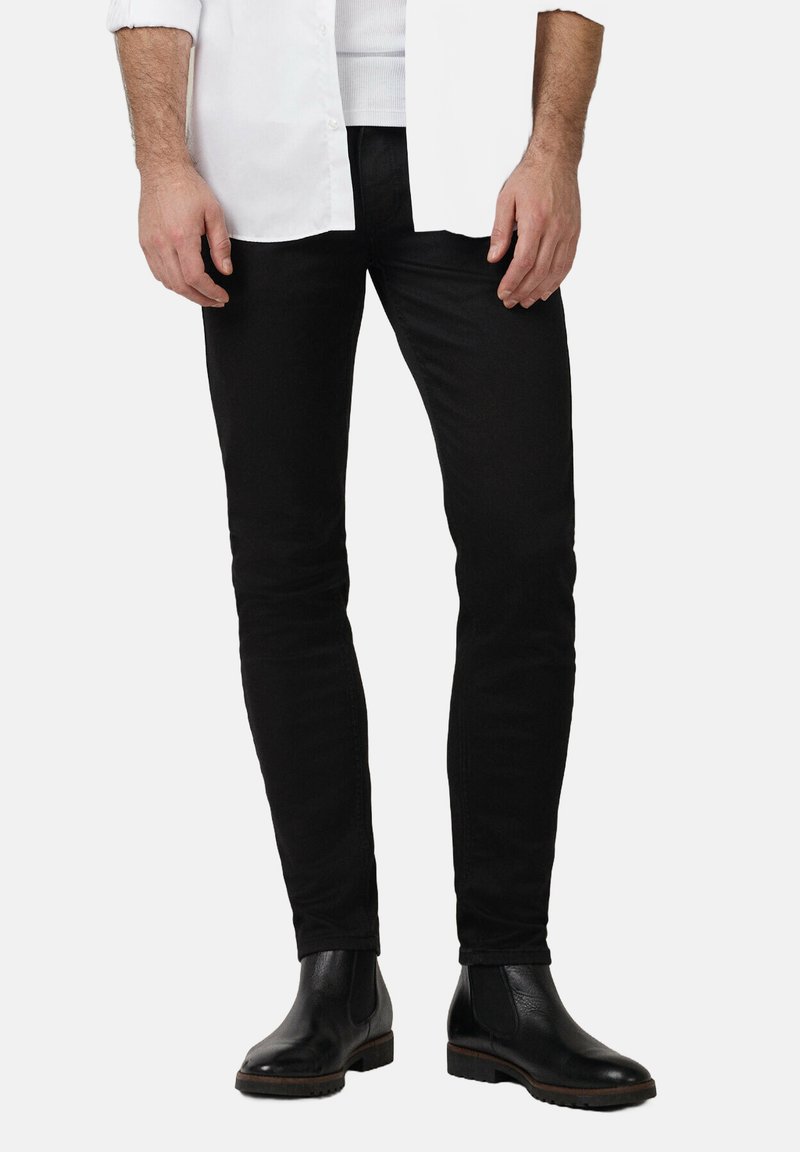 Czarne jeansy slim fit wykonane z denimu, charakteryzujące się gładką teksturą i klasycznym designem pięciu kieszeni, w połączeniu z czarnymi botkami Chelsea.