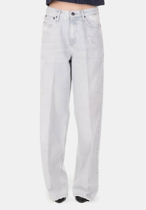 Jeans grigio chiaro a gamba larga con leggero effetto consumato, vita alta, chiusura frontale con bottone e cerniera, indossati con scarpe nere appuntite.