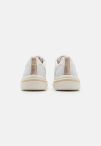 Sneaker bianco con rifinitura testurizzata, accento beige nella parte del tallone e suola in gomma color crema; design a taglio basso per un look casual.