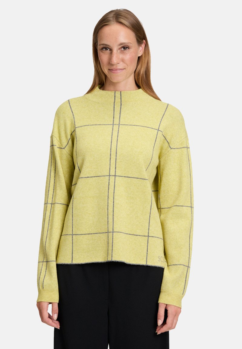 Żółty sweter w szary wzór w kratkę, z wysokim kołnierzem i obniżonymi szwami ramion. Tkanina wydaje się miękka i teksturowana.