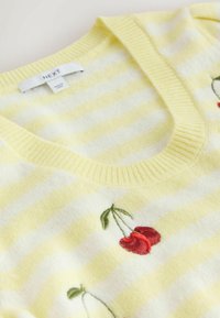 Kollaste ja valgete triipudega V-kaelusega kampsun, millel on tikitud punased kirssid ja rohelised lehed. Pehme tekstuur ja soonikkoeline kaelus.