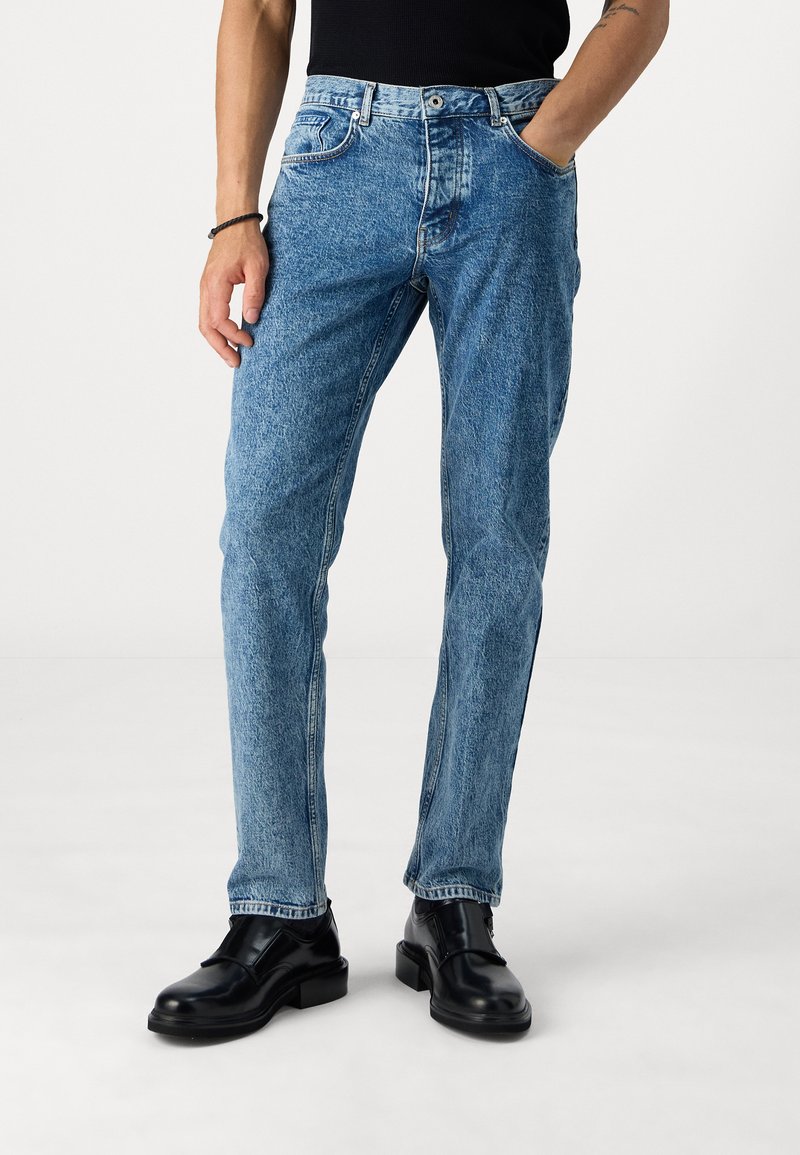 Light blue denim jeans with a straight fit, five-pocket design, and a slightly faded texture. Worn with black leather shoes.