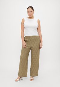 Λευκή αμάνικη μπλούζα, ελιάς πράσινο παντελόνι με φαρδιά ποδιά και σχέδιο διαμαντιού, και λευκά σανδάλια με χοντρή φτέρνα. Απλός σχεδιασμός και υφή υφάσματος.